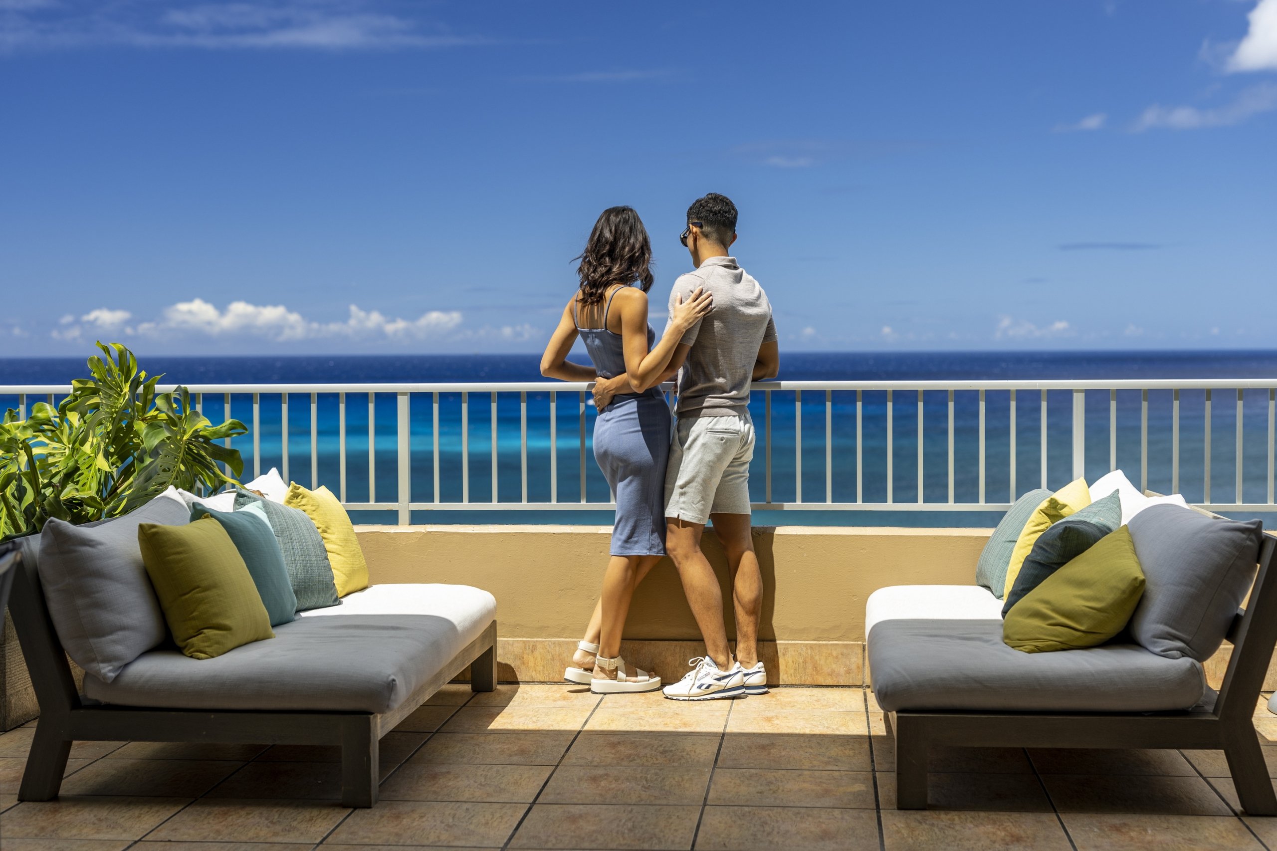 Couple having a romantic moment, enjoying Twin Fin's ocean view room with private balcony.