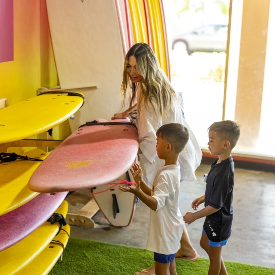 Mother choosing surfboard for two children