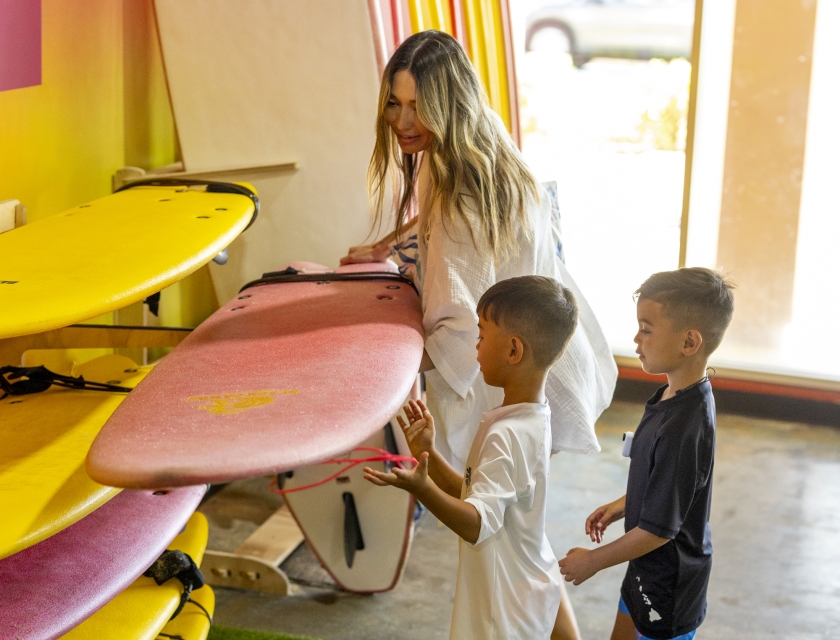Mother choosing surfboard for two children