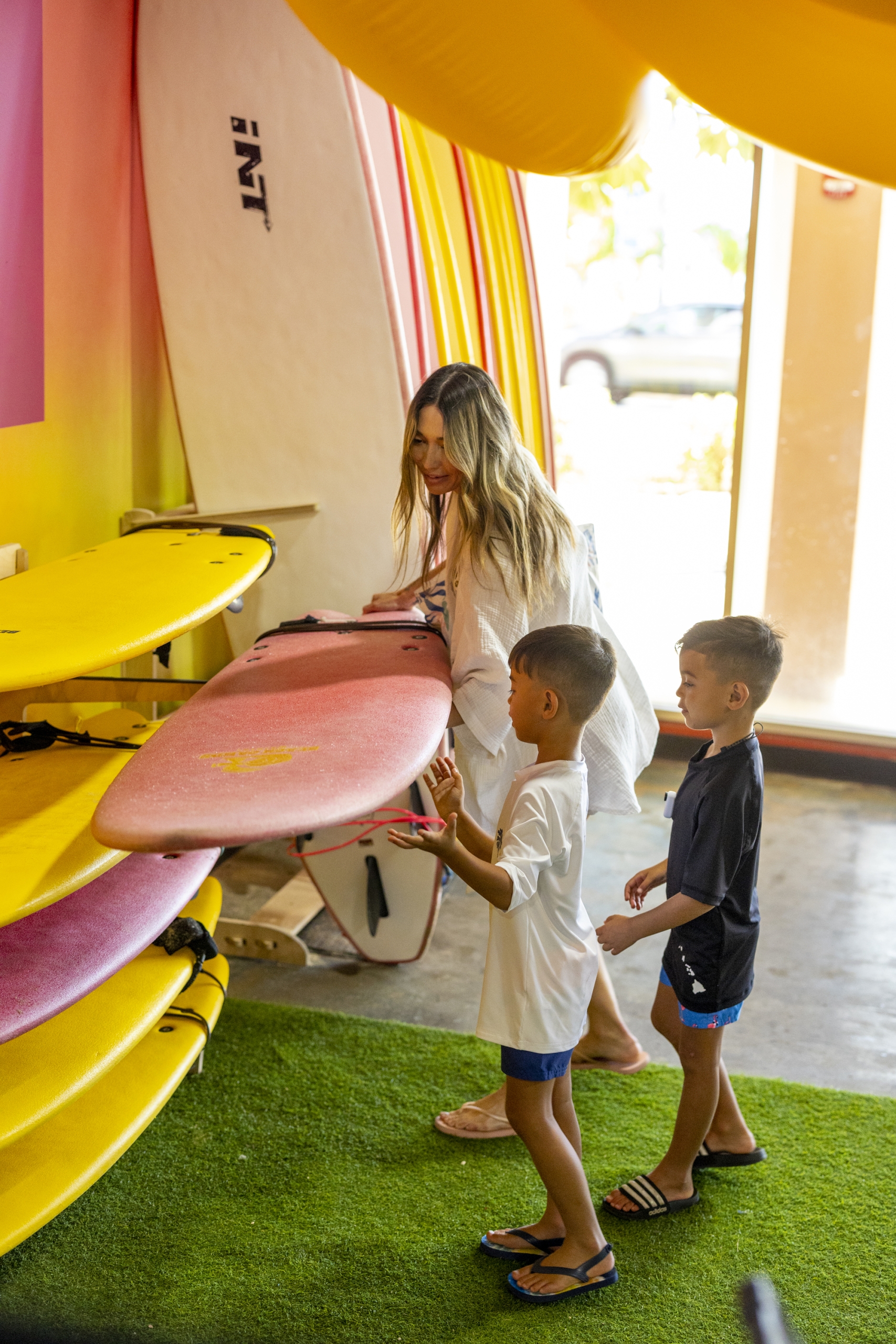 Mother choosing surfboard for two children