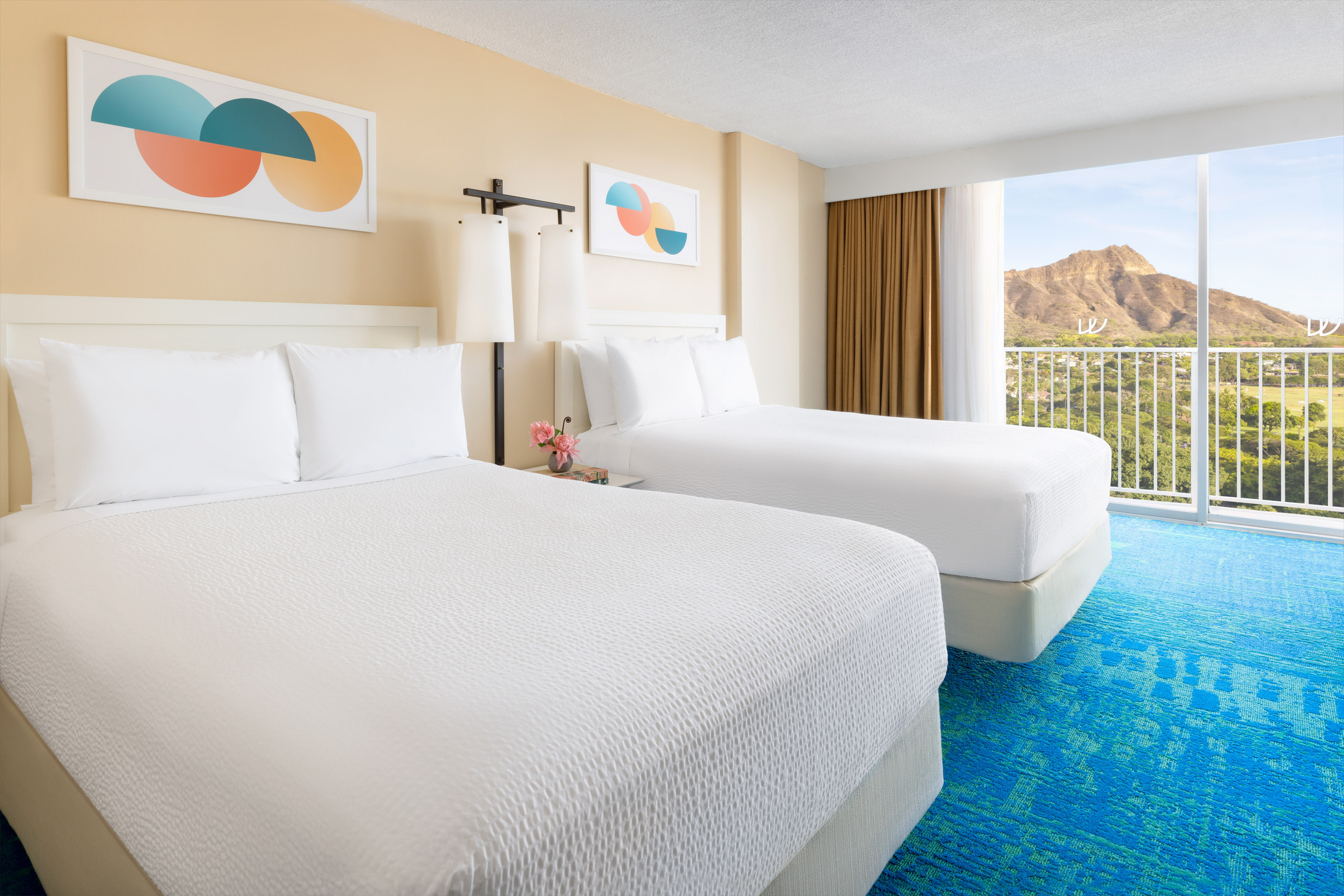 A hotel room with two beds, a balcony, and a view of a mountain.