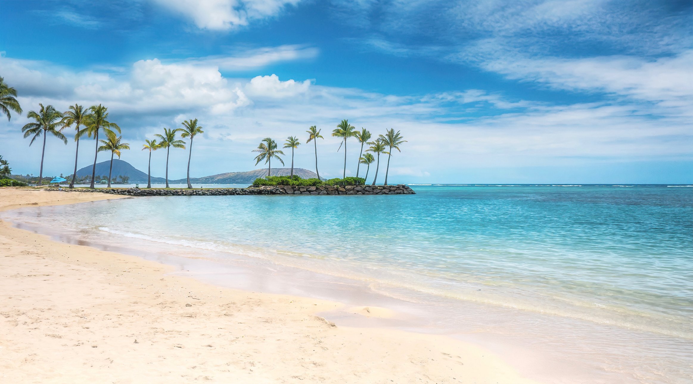 Kahala Beach with a view of coconut palm trees and Diamond Head in the background