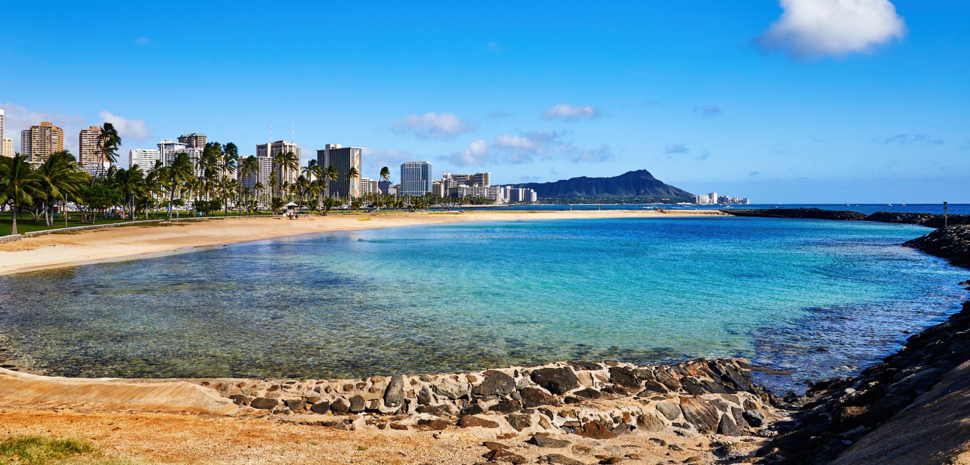 Most popular beach in Honolulu; A beautiful sunset over a calm ocean with vibrant orange and pink hues reflecting on the water.