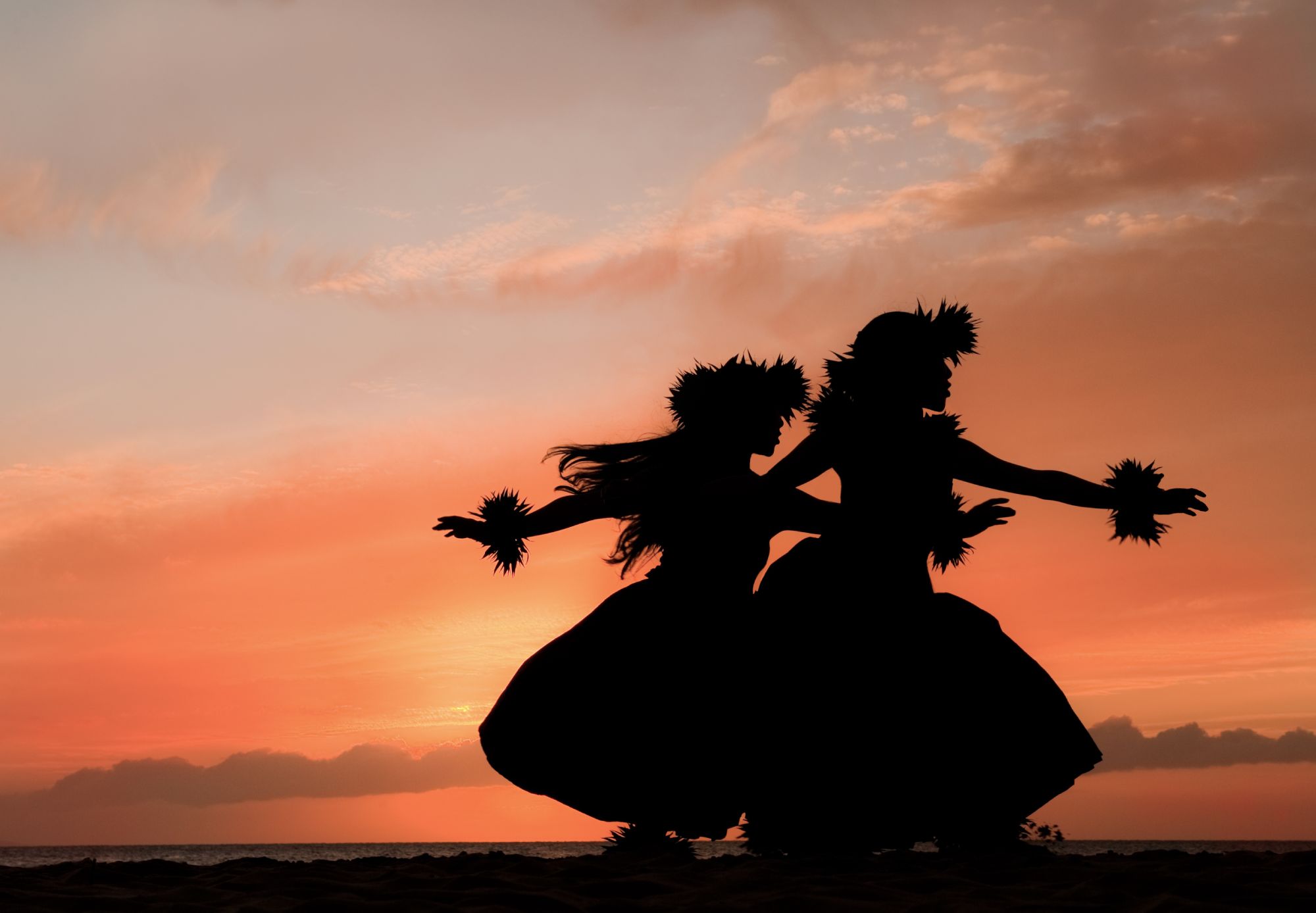 Two Hawaiian hula dancers move gracefully before the warm glow of the tropical sunset.