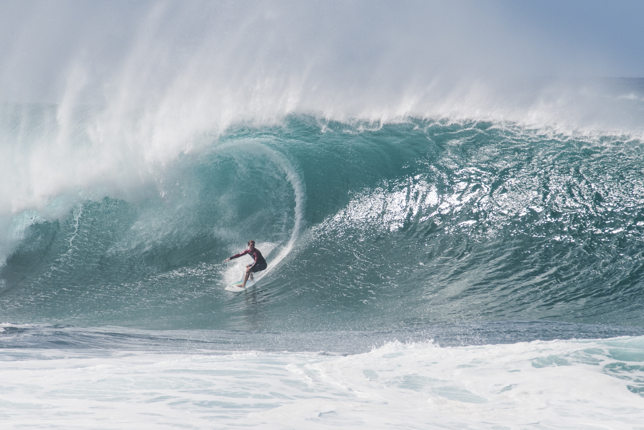 A surfer lines up a very large wave in Oahu