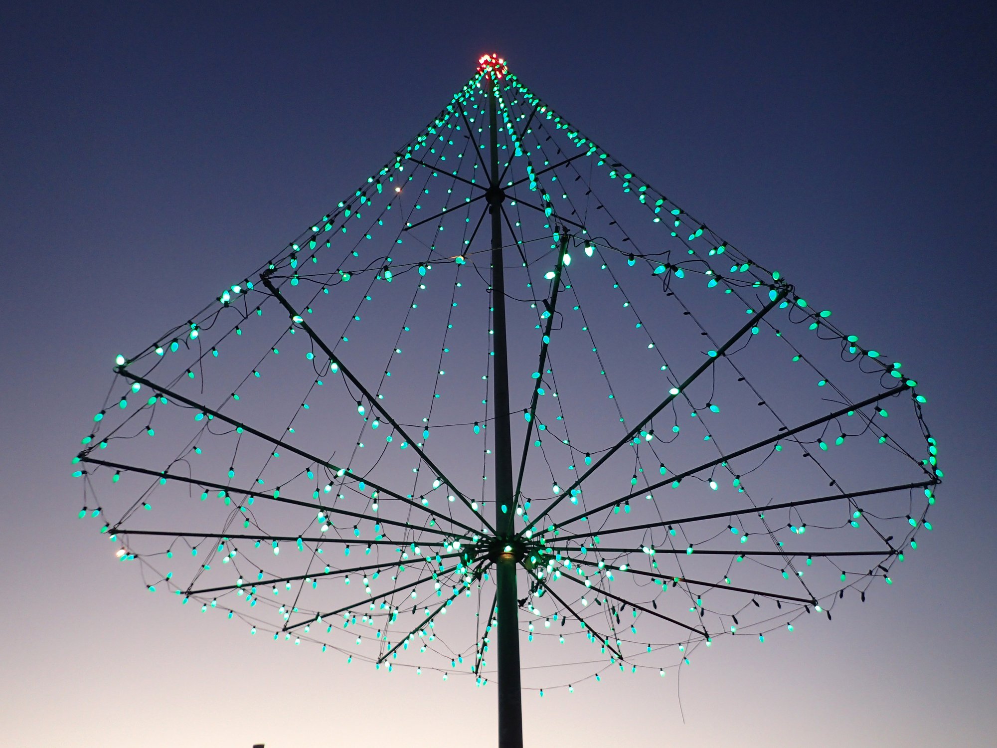 The Kaimuki Christmas tree on top Pu'u O Kaimuki at dusk on with cityscape of Oahu, Hawaii.