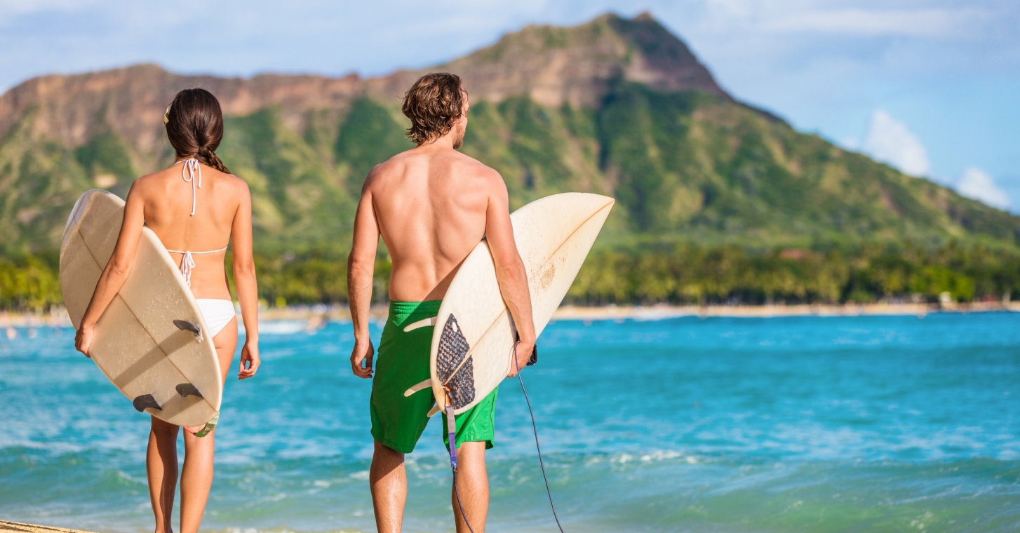 A man and woman holding surf board getting ready to surf at Waikiki beach