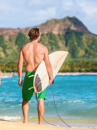 A man and woman holding surf board getting ready to surf at Waikiki beach