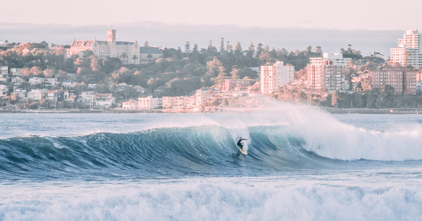 Manly Beach featuring rolling hills, a clear blue sky, and a tranquil lake reflecting the surrounding nature.