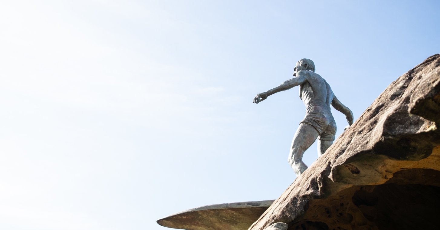 Manly Beach Duke Statue depicting a man skillfully balancing on a surfboard, capturing the essence of surfing culture and artistry.