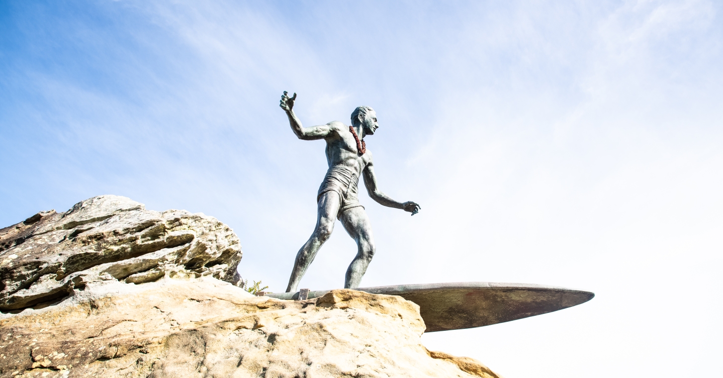 Duke Kahanamoku Statue; A statue of a surfer poised on a rock, capturing the essence of surfing and coastal adventure.
