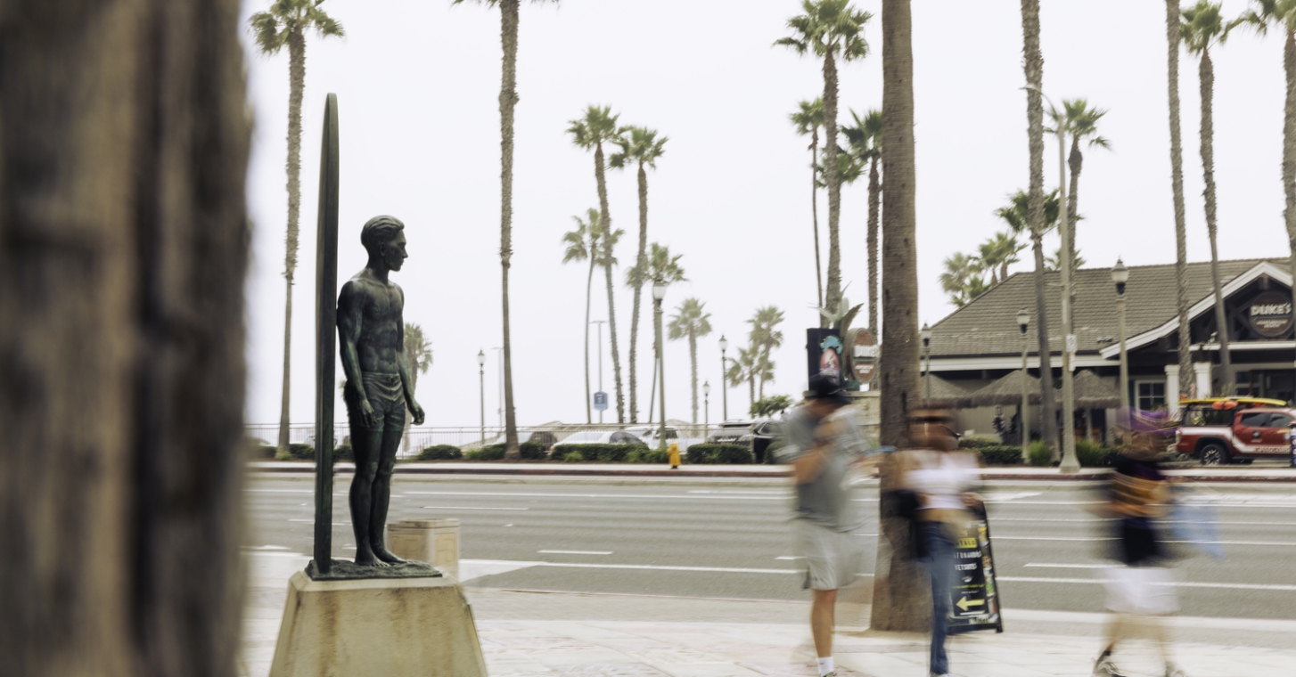 People walking by the Duke Kahanamoku Statue in southern california
