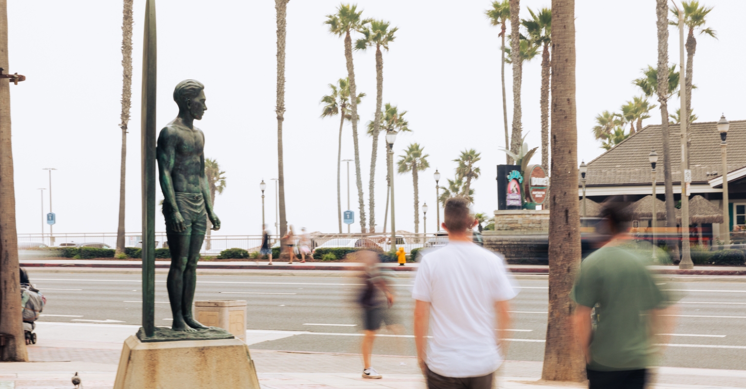 travelers visit the Duke Kahanamoku Statue along the Pacific Coast Highway in Huntington Beach